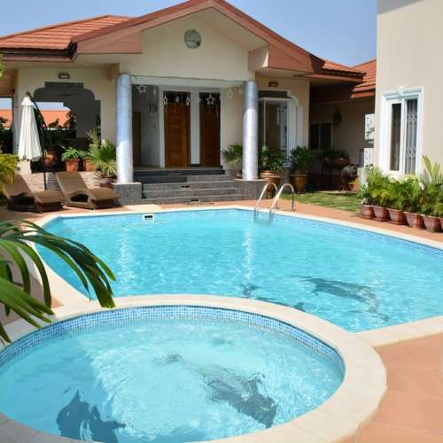 A swimming pool with a kids pool in front of a beautiful house in Ghana