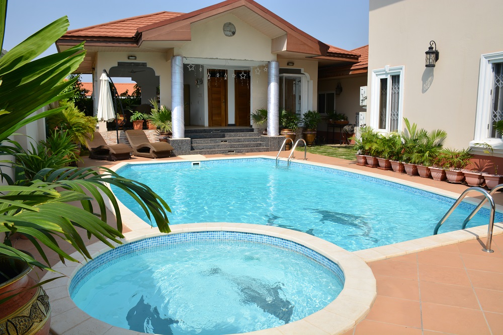 A swimming pool with a kids pool in front of a beautiful house in Ghana